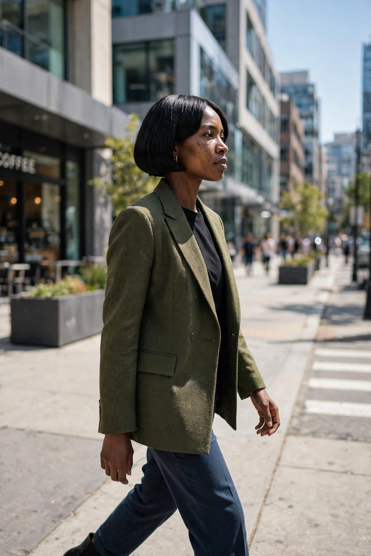 Black woman with a sharp micro bob walking on a city sidewalk