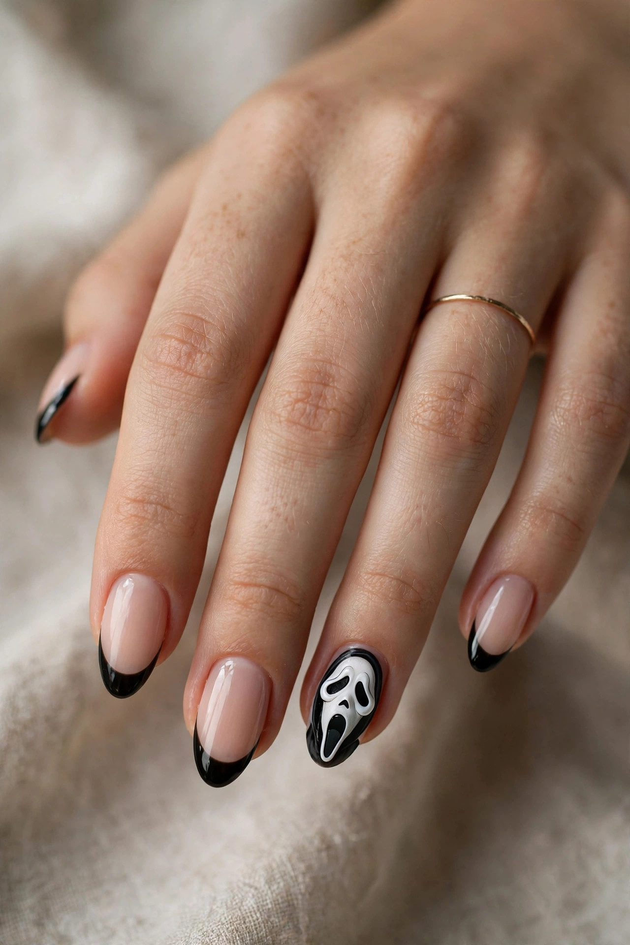 Teen hand with black French tip nails and Ghostface mask accent nail