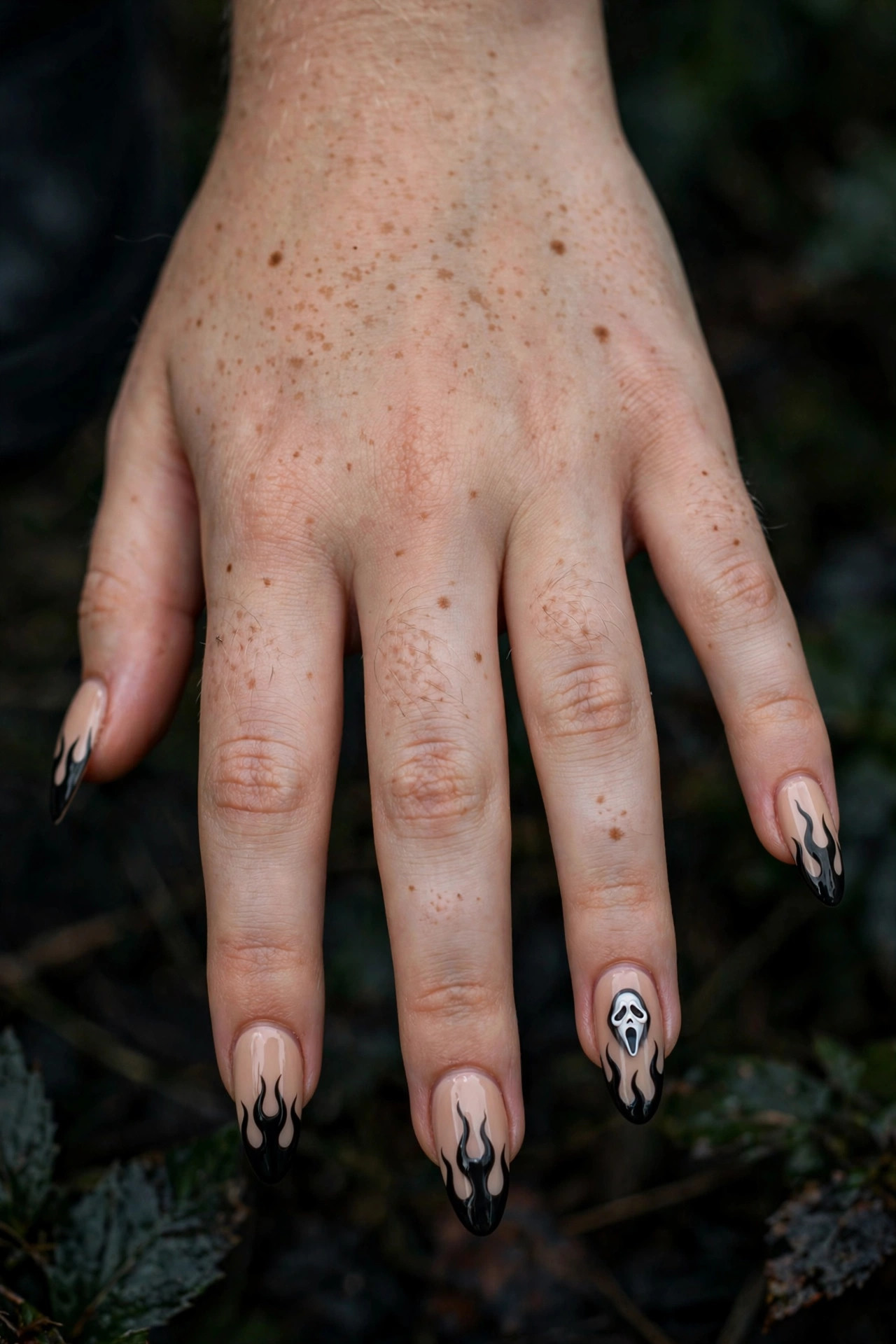 Teen hand with black flame tip nails and tiny Ghostface accent