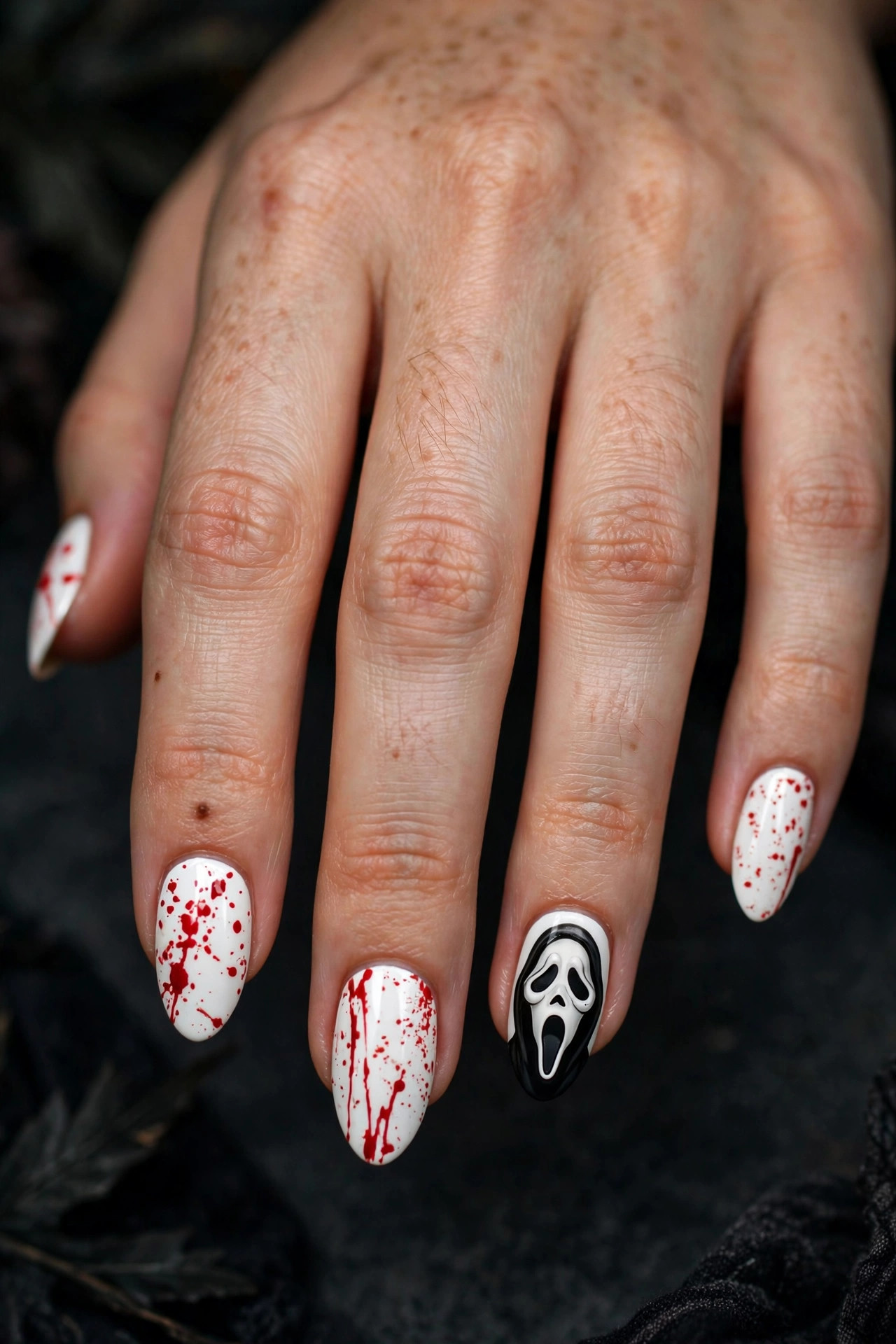 Teen hand with white nails and red blood splatter nail art