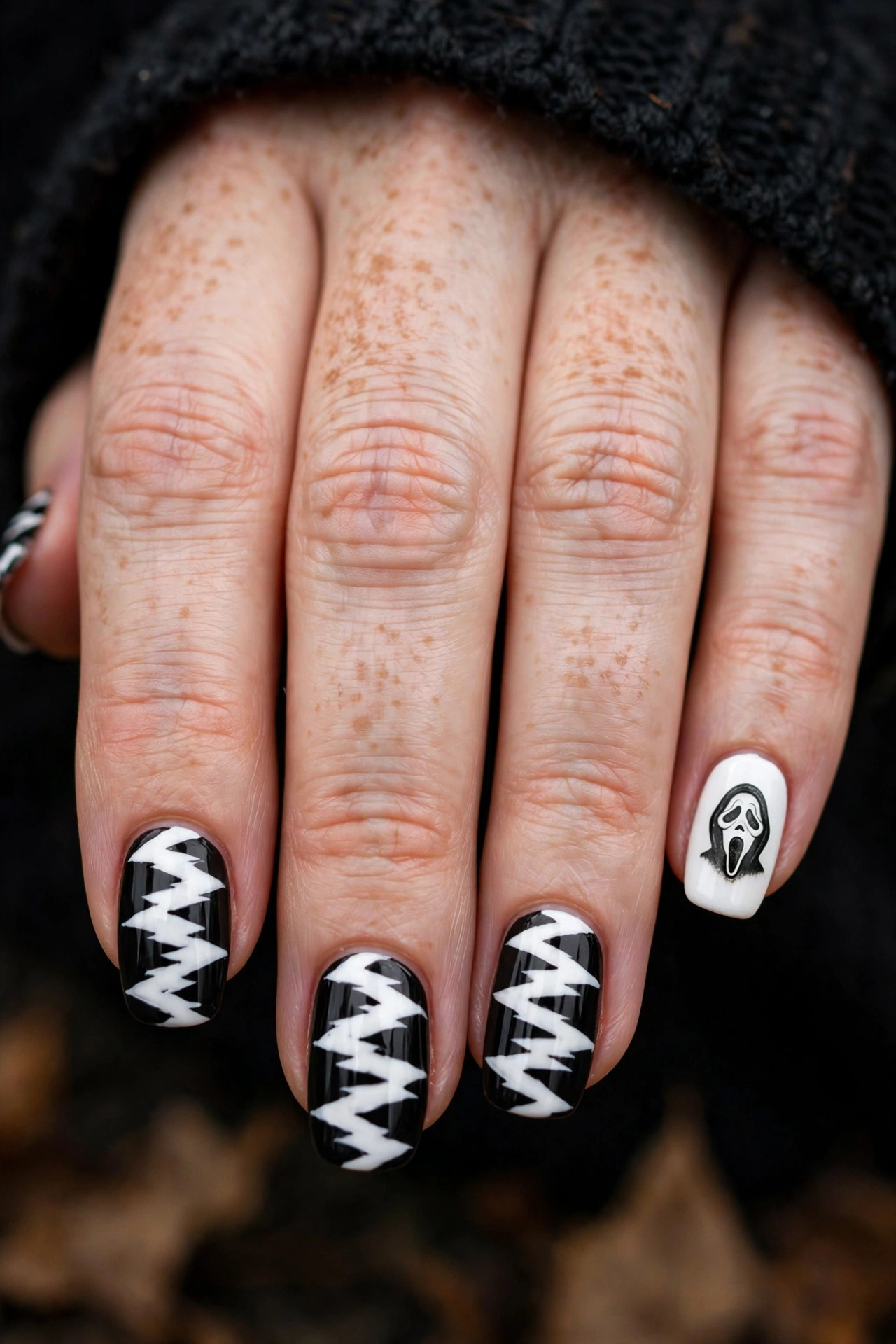 Teen hand with black and white striped robe-inspired Ghostface nails