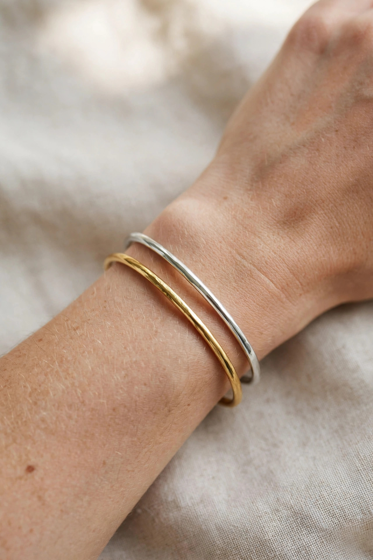 Close-up of a wrist wearing gold and silver bracelets to test skin undertone in natural light