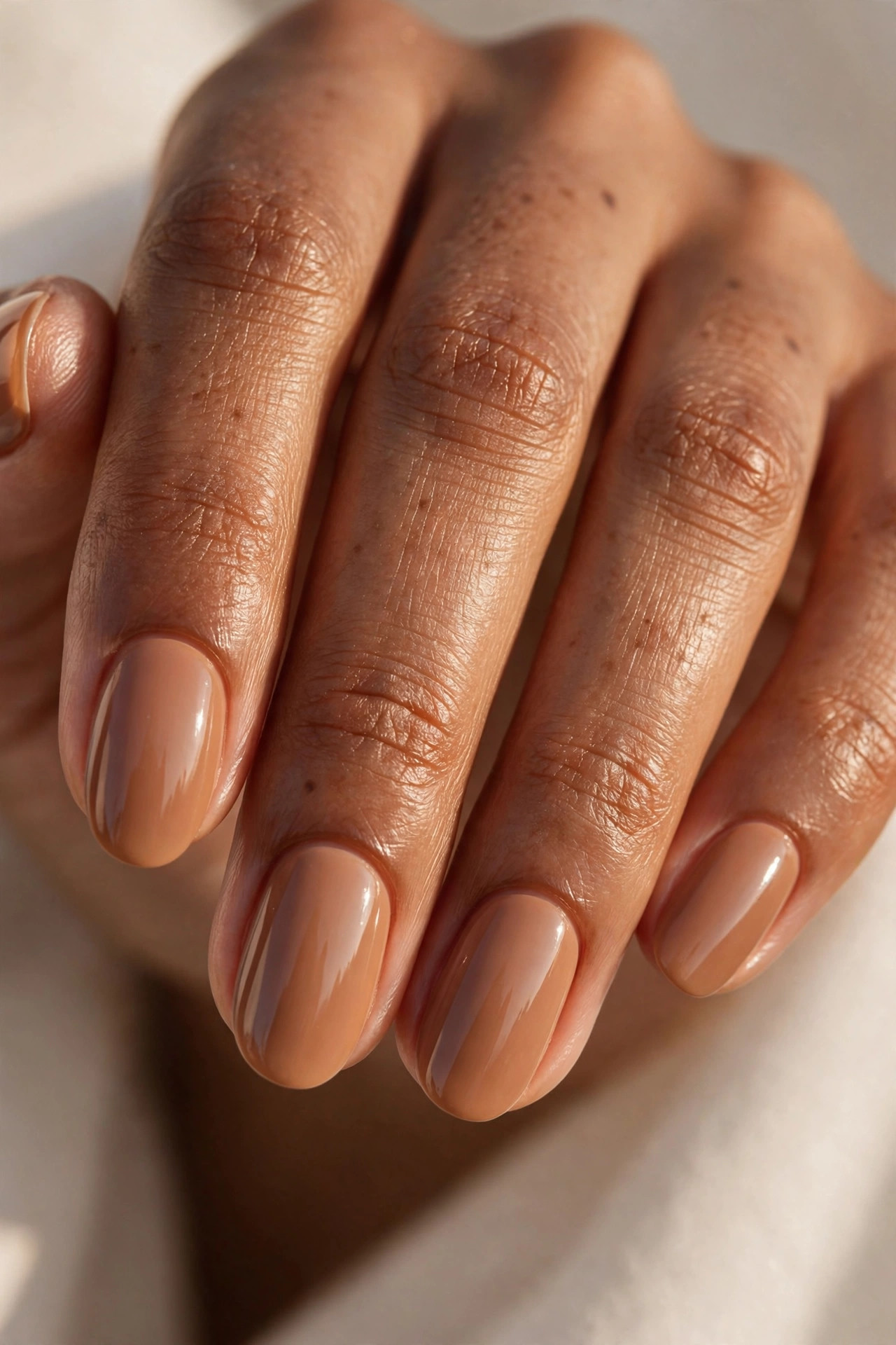 Medium-deep skin hand with toffee caramel nude nail polish